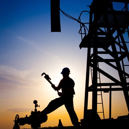 Oilfield worker with oil derrick in the background