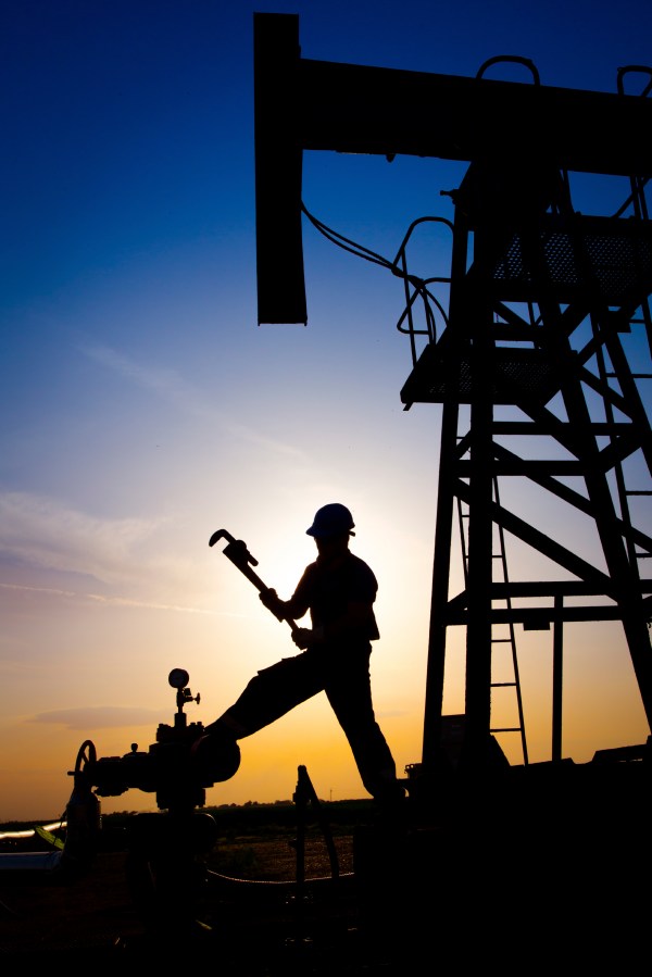 Oilfield worker with oil derrick in the background